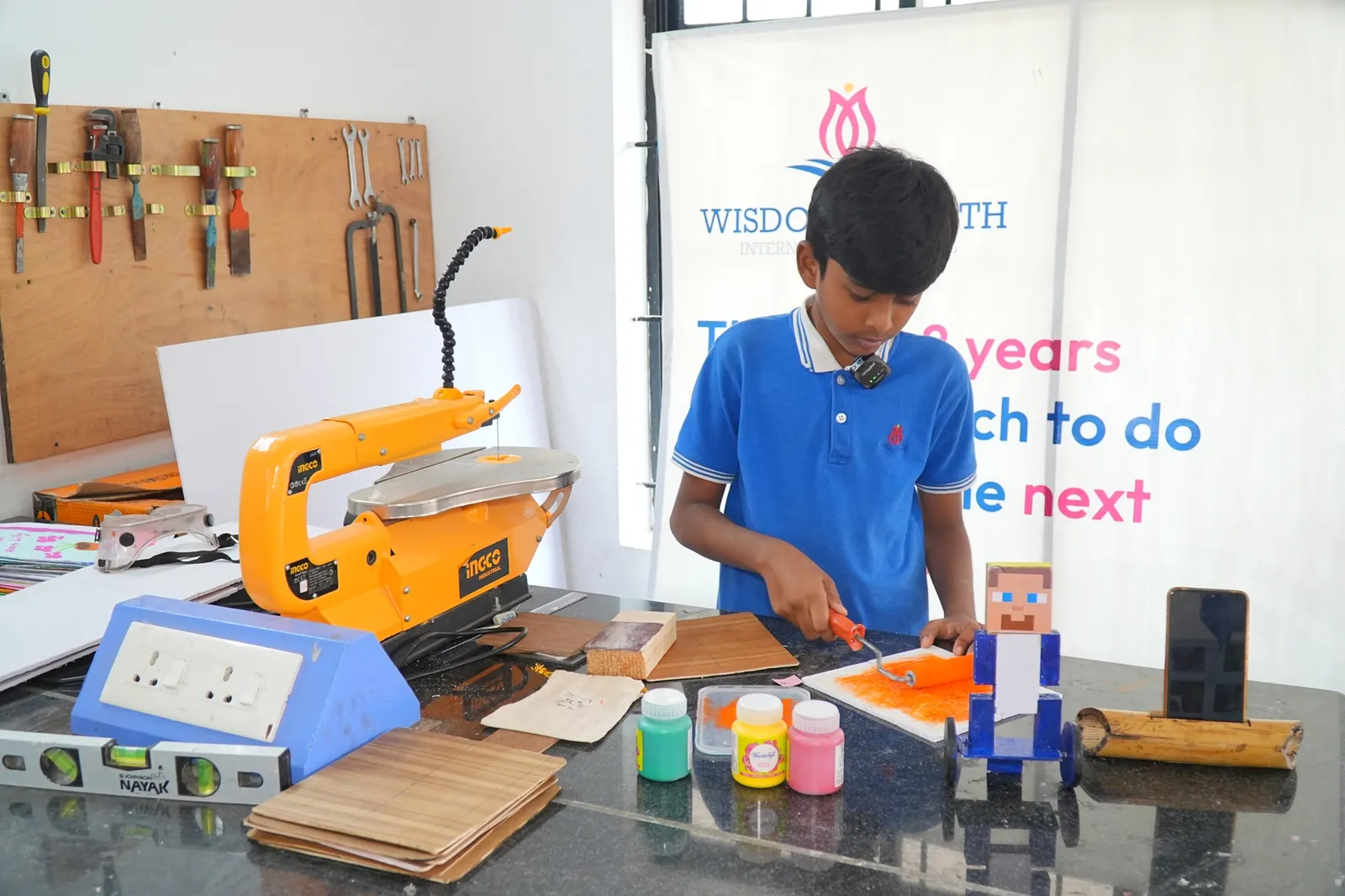 Student painting a woodwork project in the makerspace