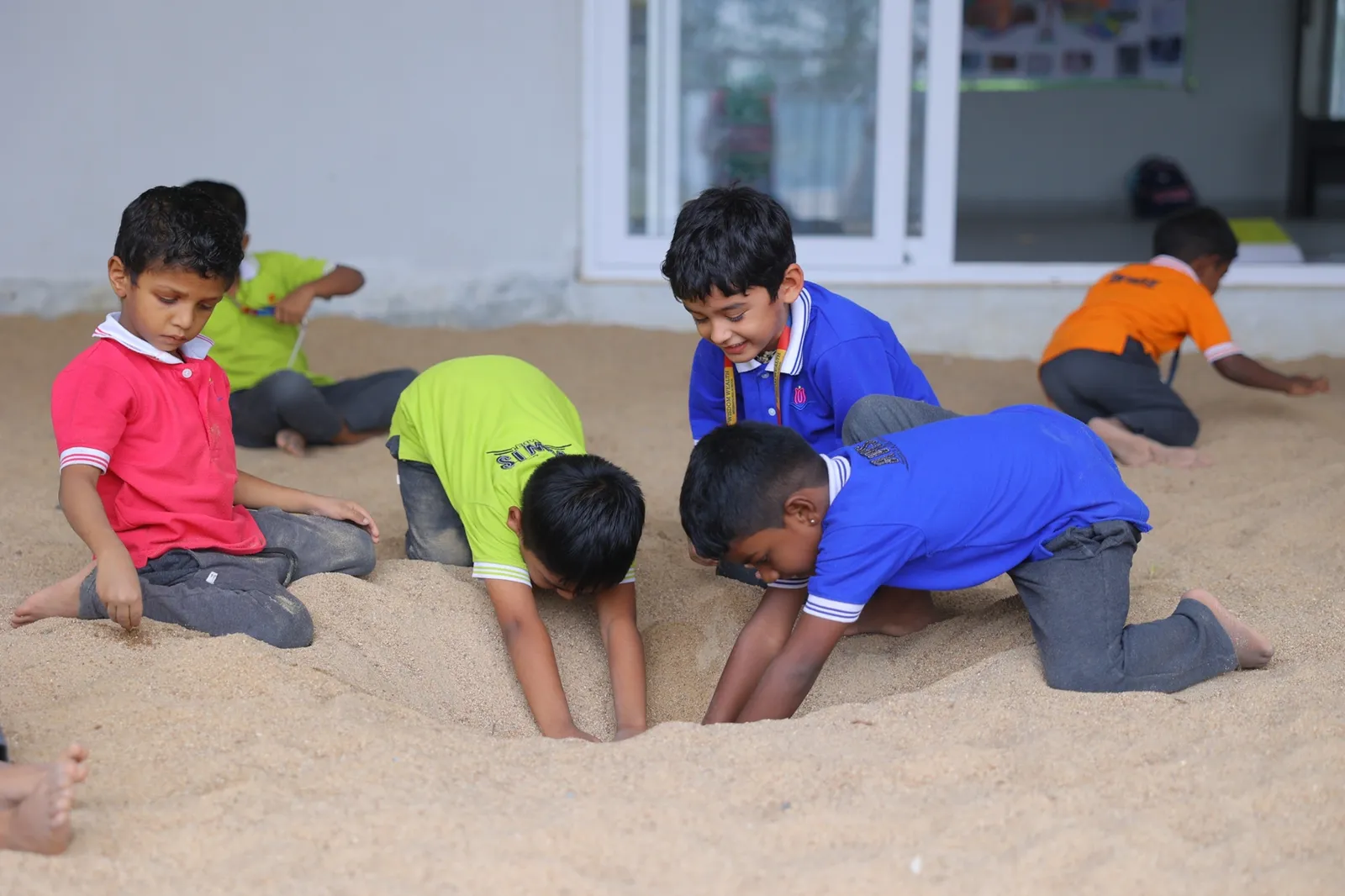 Young students digging together in the sand pit